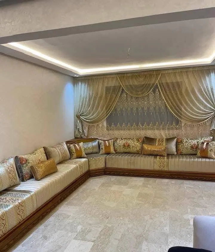 صالون مغربي بيج وذهبي على شكل U مع ستائر ذهبية